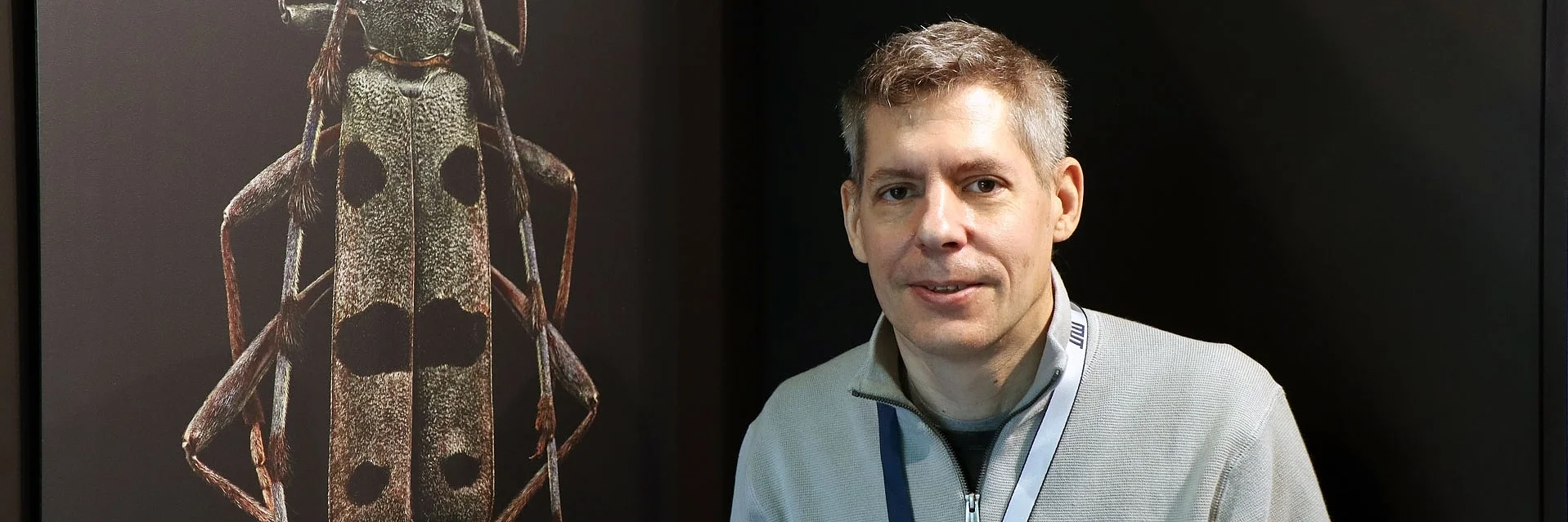 Ein Mann neben einem lebensgroßen Portrait eines Käfers