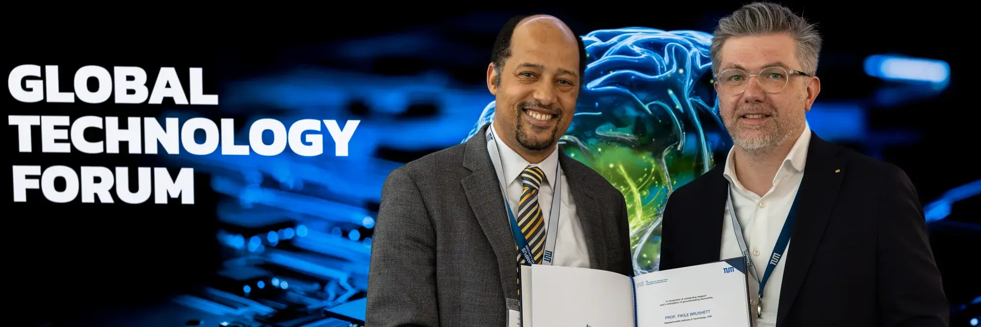 Zwei Männer halten eine Urkunde vor dem Hintergrund des Global Technology Forums