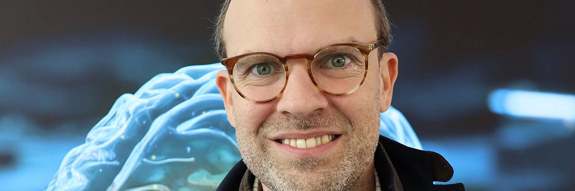 a man in front of a bllue screen looking into the camera