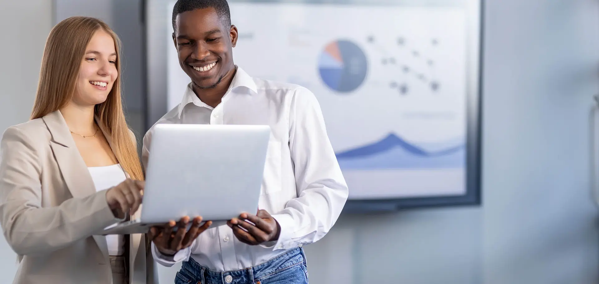 Man and woman discussing a project on a laptop in a modern office space