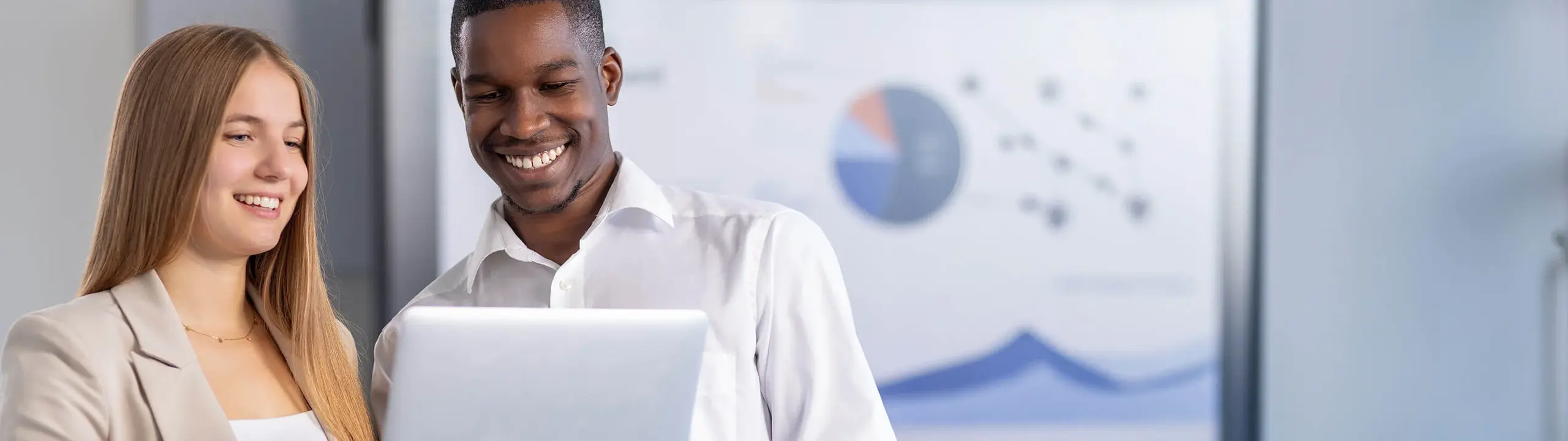 Mann und Frau besprechen ein Projekt an einem Laptop in einem modernen Büroraum