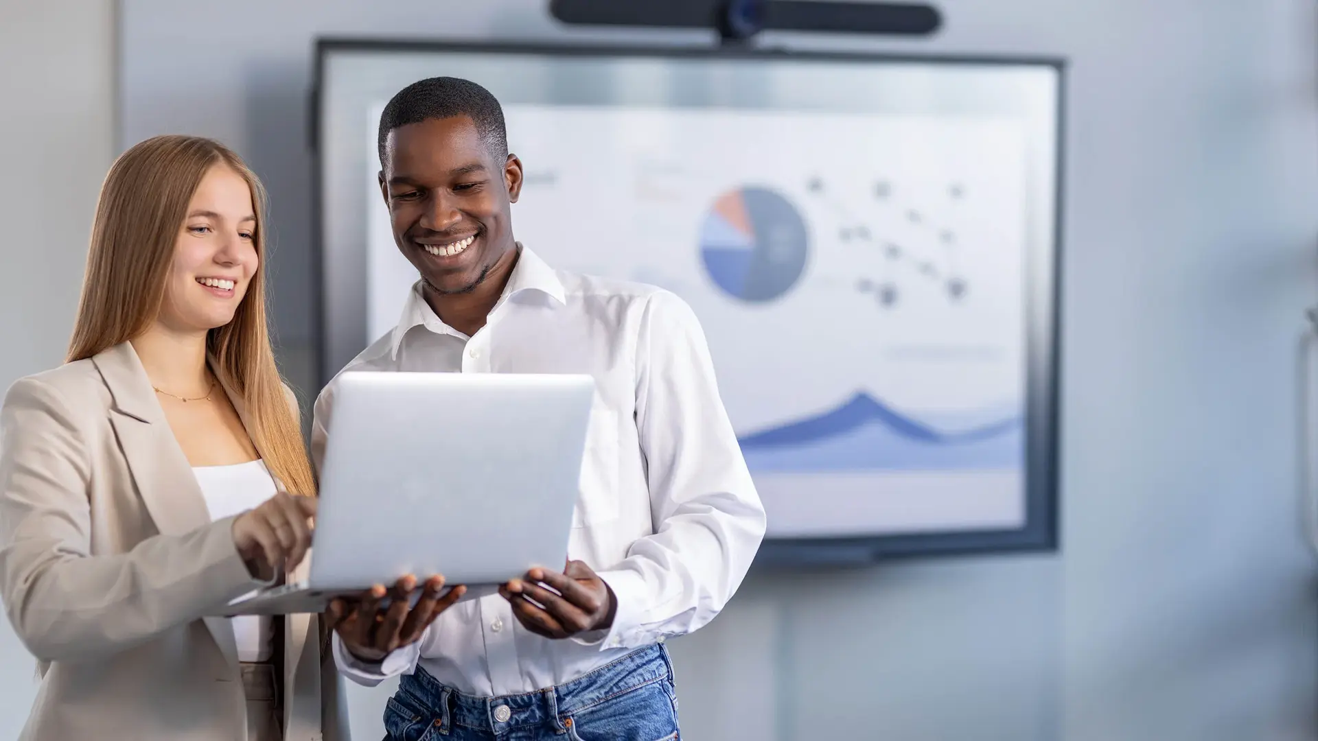 Mann und Frau besprechen ein Projekt an einem Laptop in einem modernen Büroraum