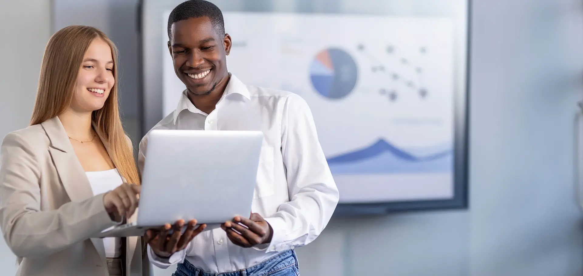 Man and woman discussing a project on a laptop in a modern office space