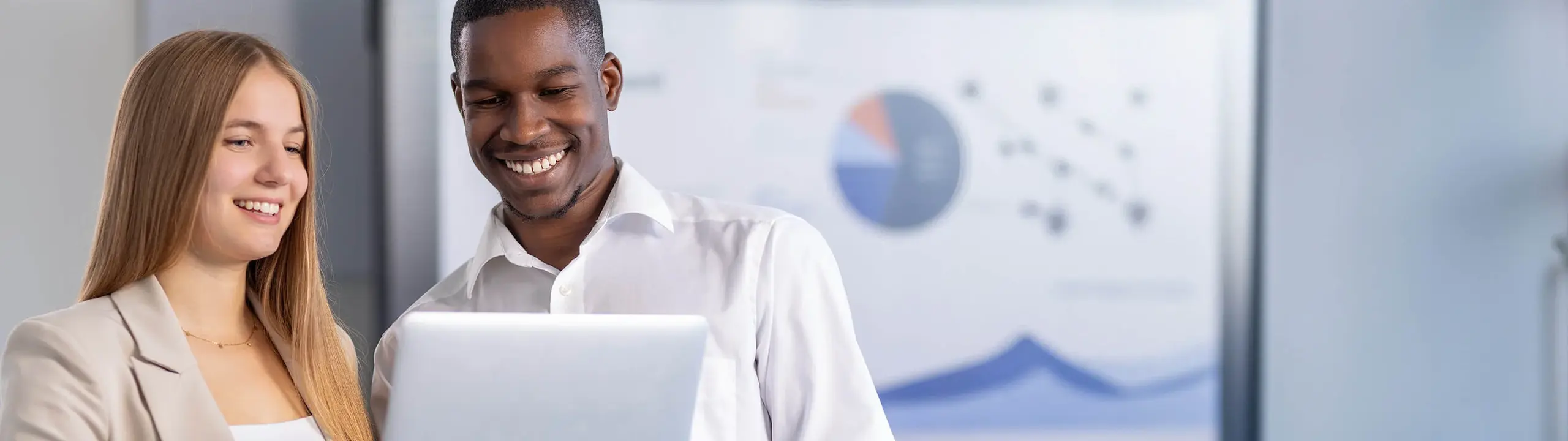 Mann und Frau besprechen ein Projekt an einem Laptop in einem modernen Büroraum