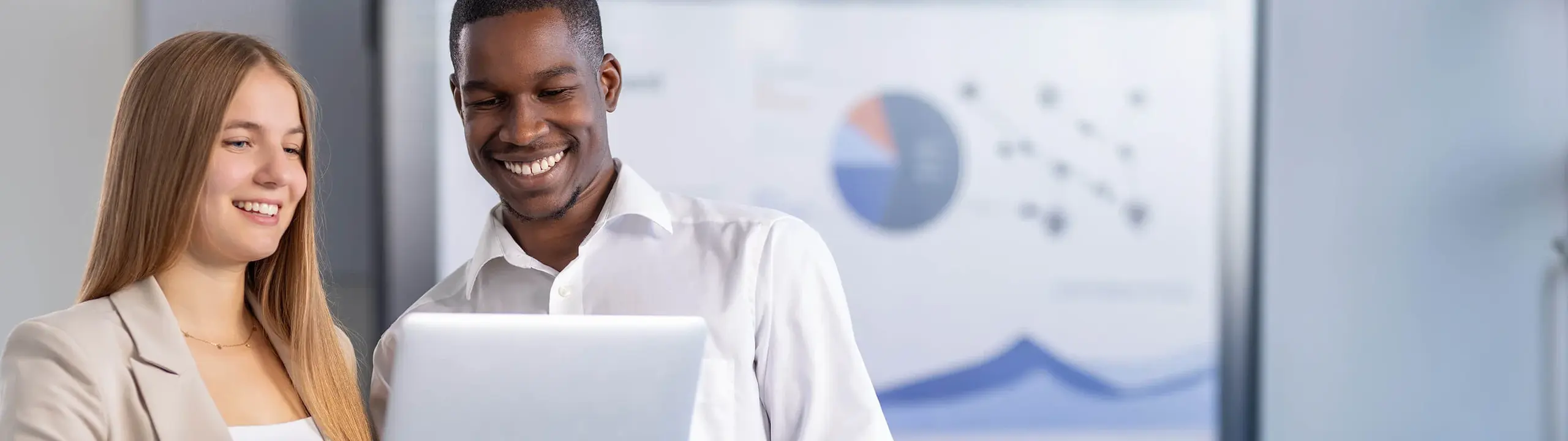 Man and woman discussing a project on a laptop in a modern office space