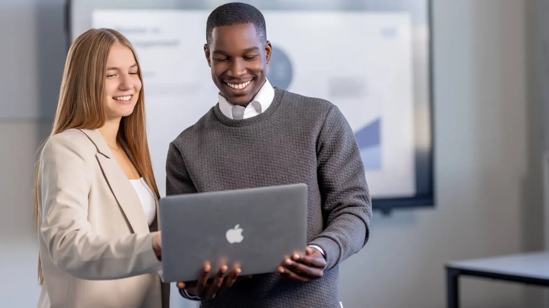 Man and woman discussing a project on a laptop in a modern office space