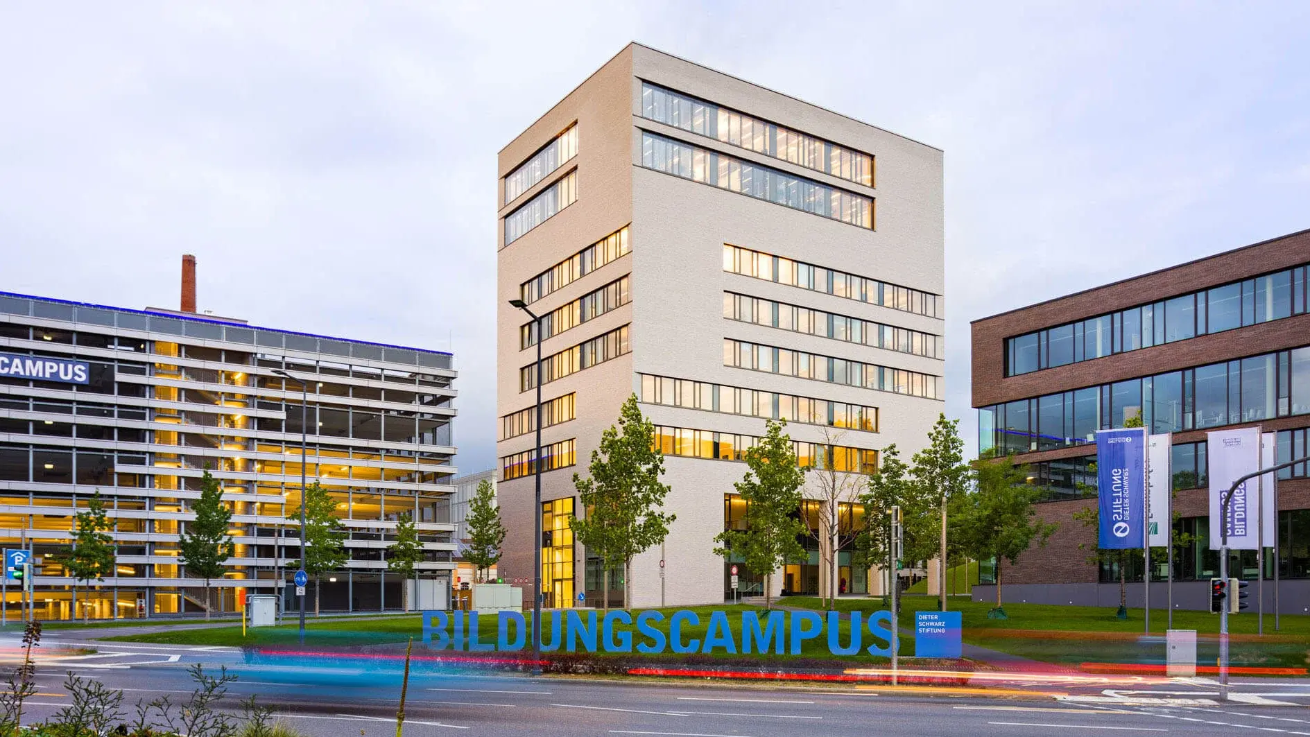 TUM-Turm mit einer Straße und dem Schild des Bildungscampus im Vordergrund