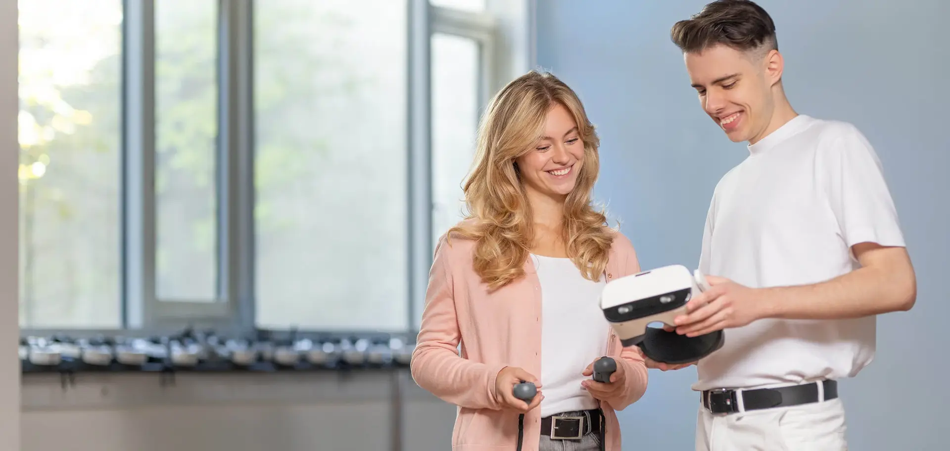 Two students looking at a tablet, and a man using a VR in the background