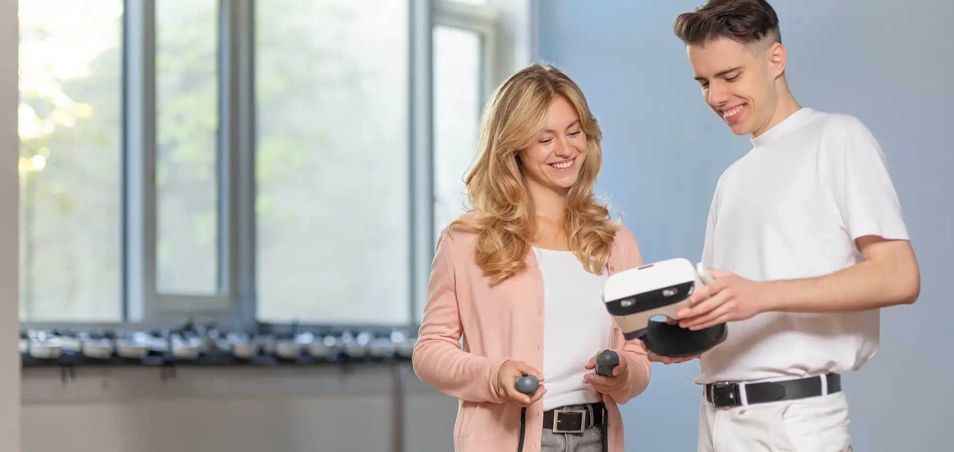 Zwei Studenten, die auf ein Tablet schauen, und ein Mann, der eine VR im Hintergrund benutzt