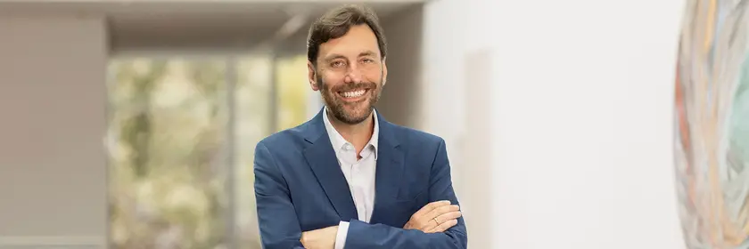 Mann in blauem Anzug, stehend, Arme verschränkt