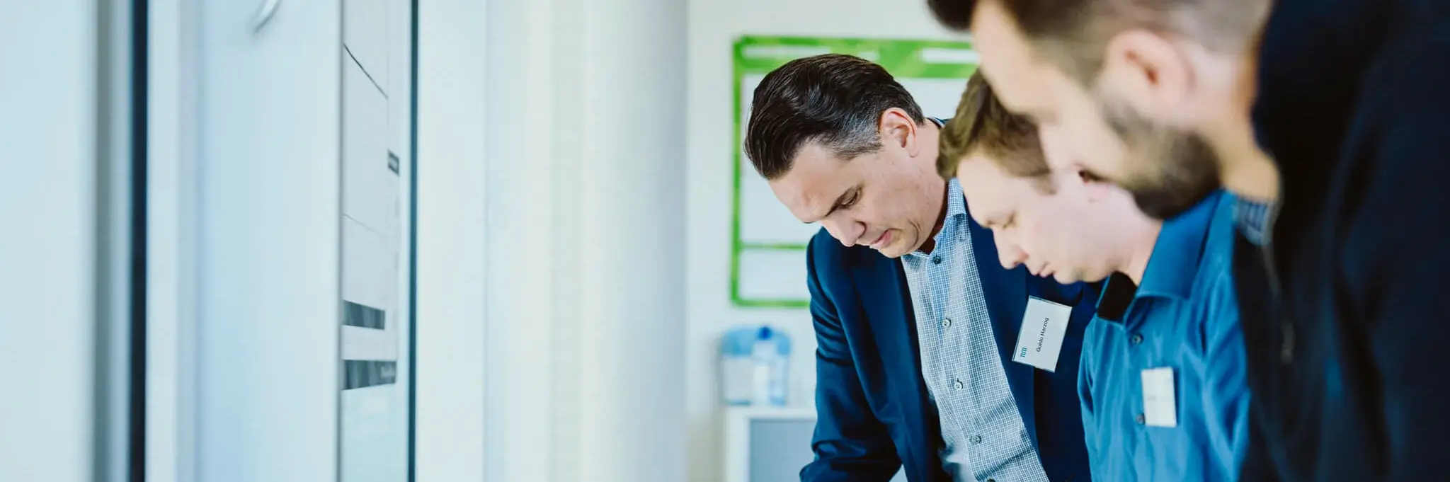 Three men standing in front of a desk and brainstorming during a working