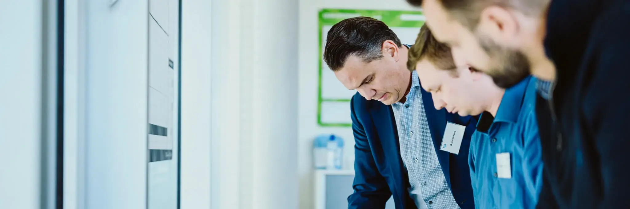 Three men standing in front of a desk and brainstorming during a working