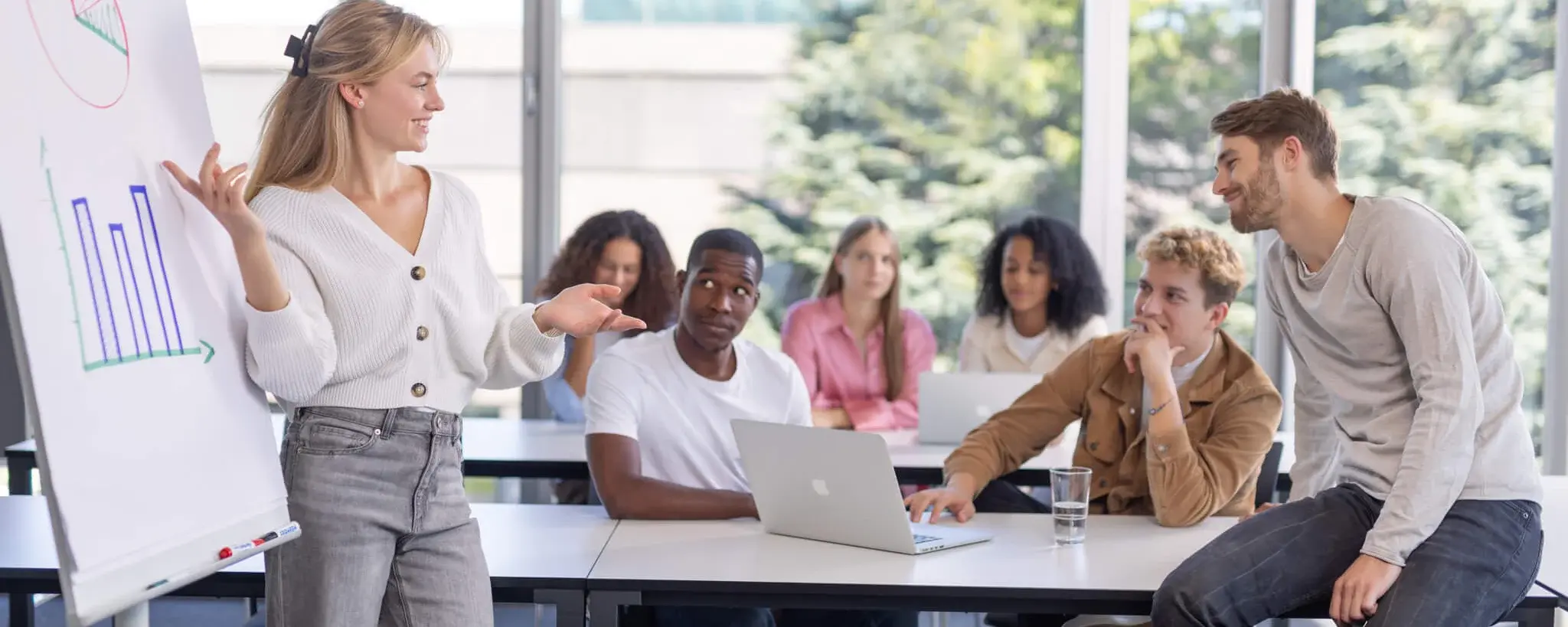 Junge Frau an einem Flipchart vor Studenten