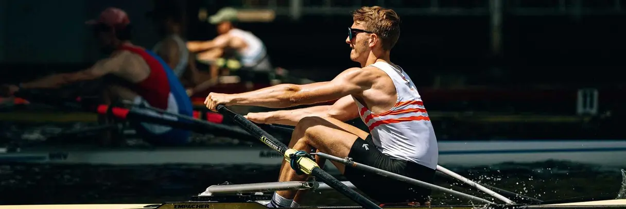 young, muscly man rowing fast on a river