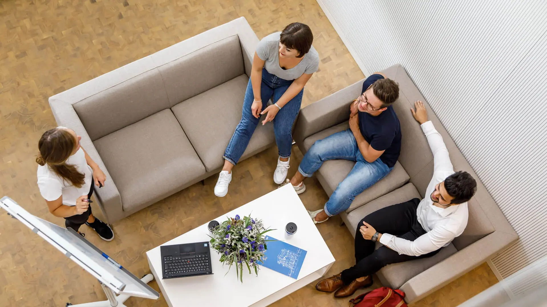 [Translate to German:] Four students sitting on two couches