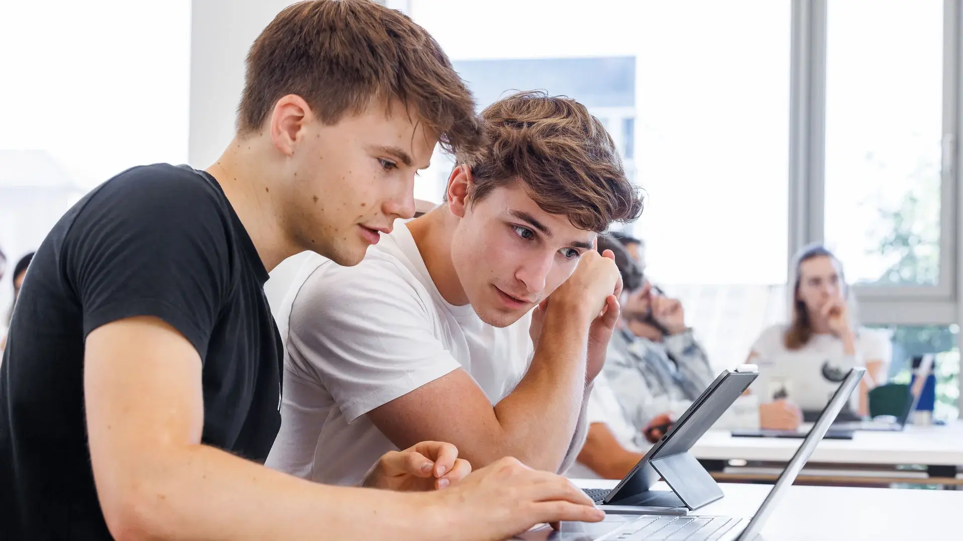 Two students looking into a laptop