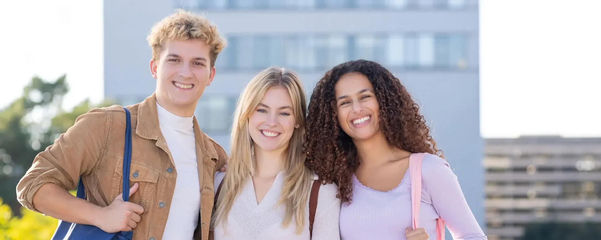 Three students sitting and talking on a lawn