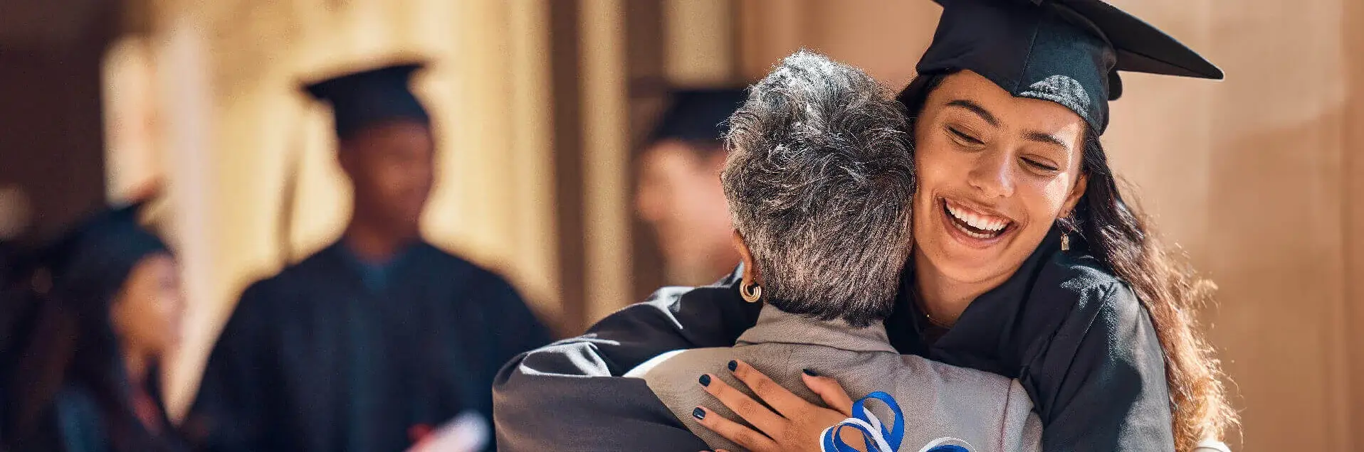 Feiernde und umarmende Studentin mit Robe