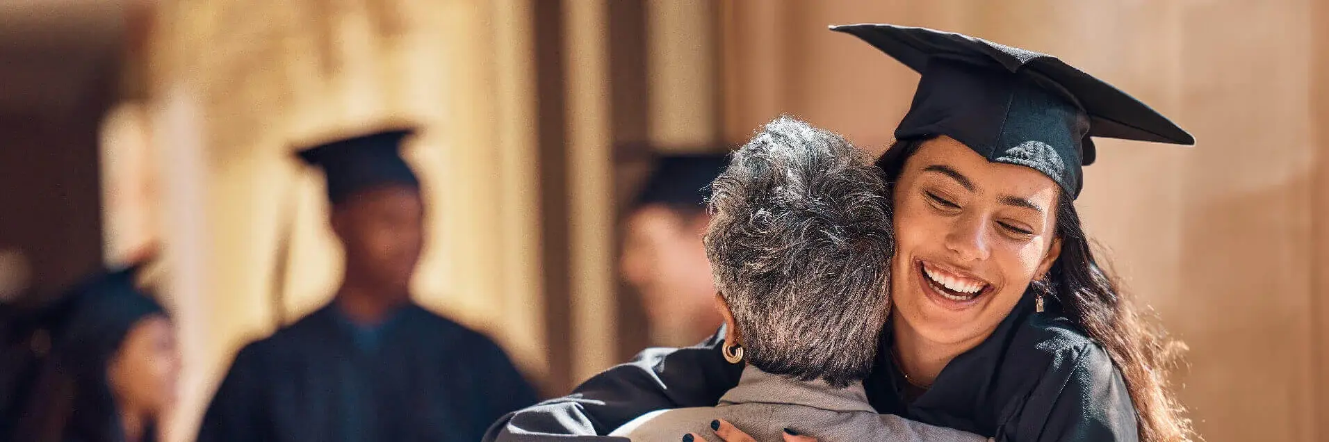 Student with gown celebrating and hugging 