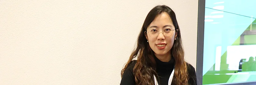 Eine junge Frau, in Schwarz gekleidet, sitzt an einem Tisch