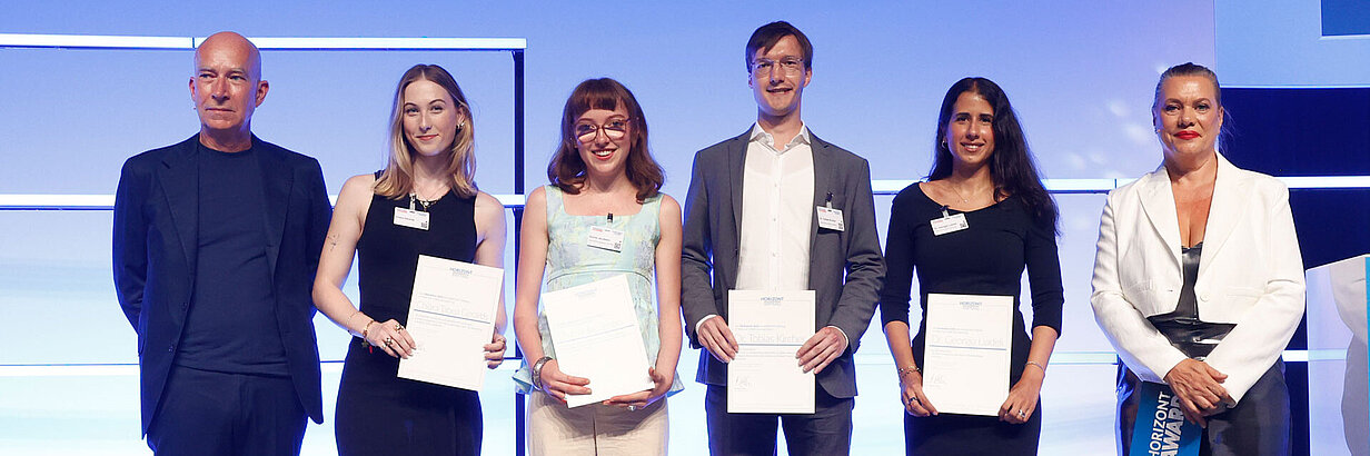A group of women and men in formal clothes standing in a line, holding certificates
