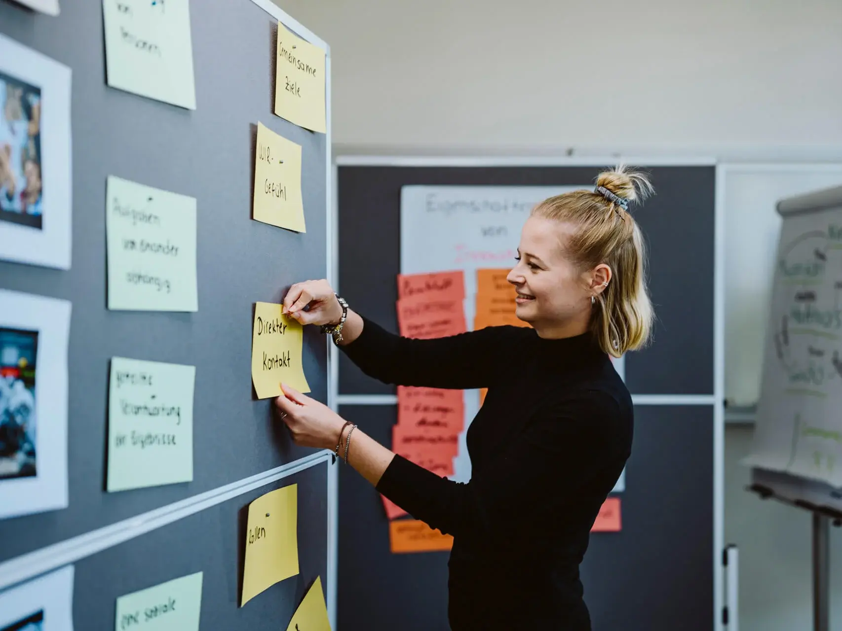 Young woman pinning notes at a metaplan wall