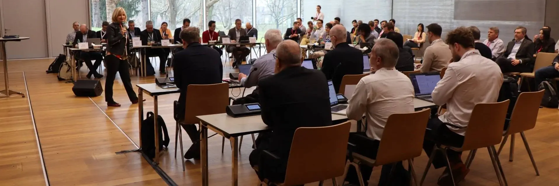A large group of professionals listening to a speaker in a classroom