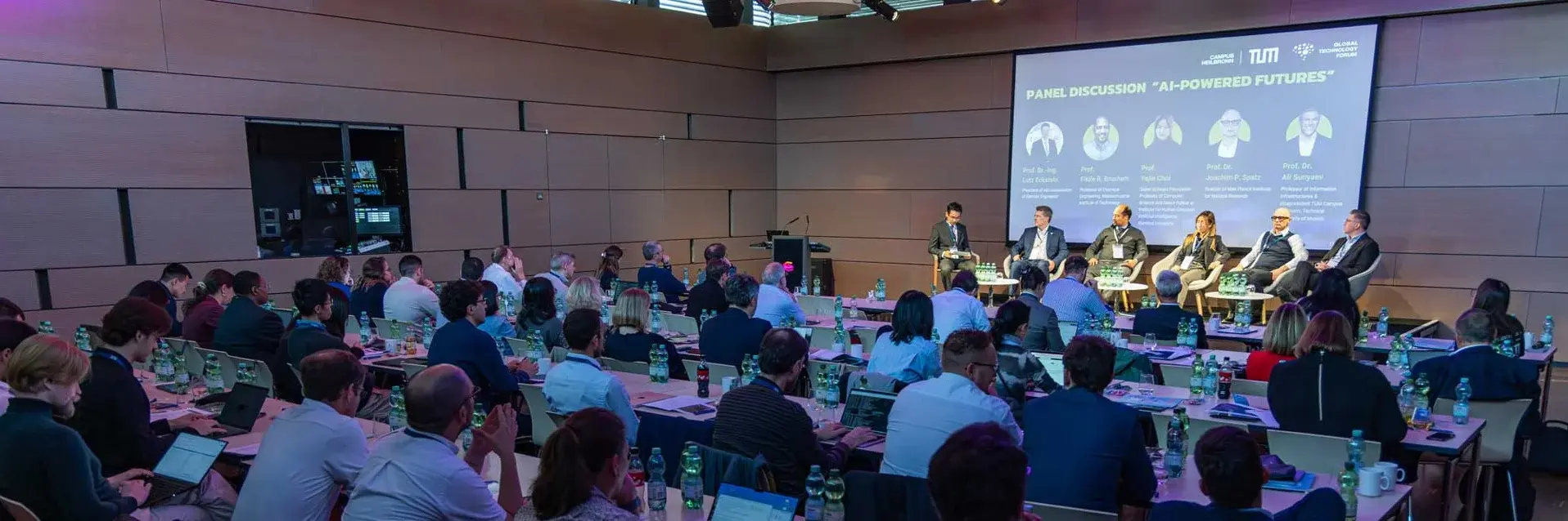 [Translate to German:] a group of people watching a panel discussion
