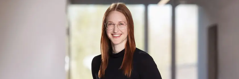 Redhaired woman, black dressed, standing, looking into the camera