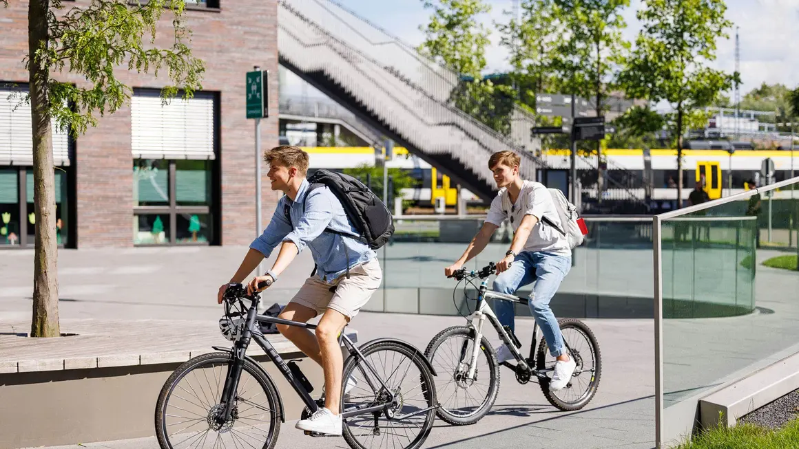 Zwei Personen fahren auf dem Campus Fahrrad