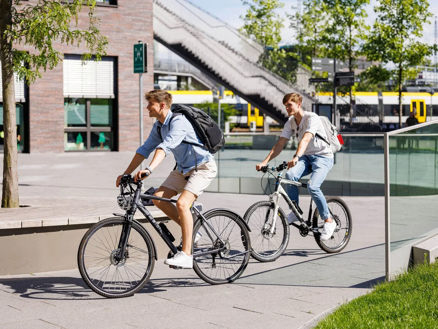 Zwei Personen fahren auf dem Campus Fahrrad