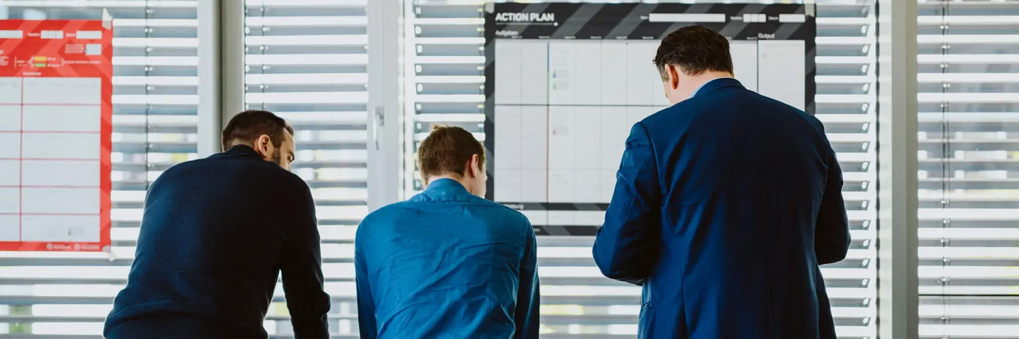 Drei Männer lehnen an einem Tisch und machen ein Brainstorming