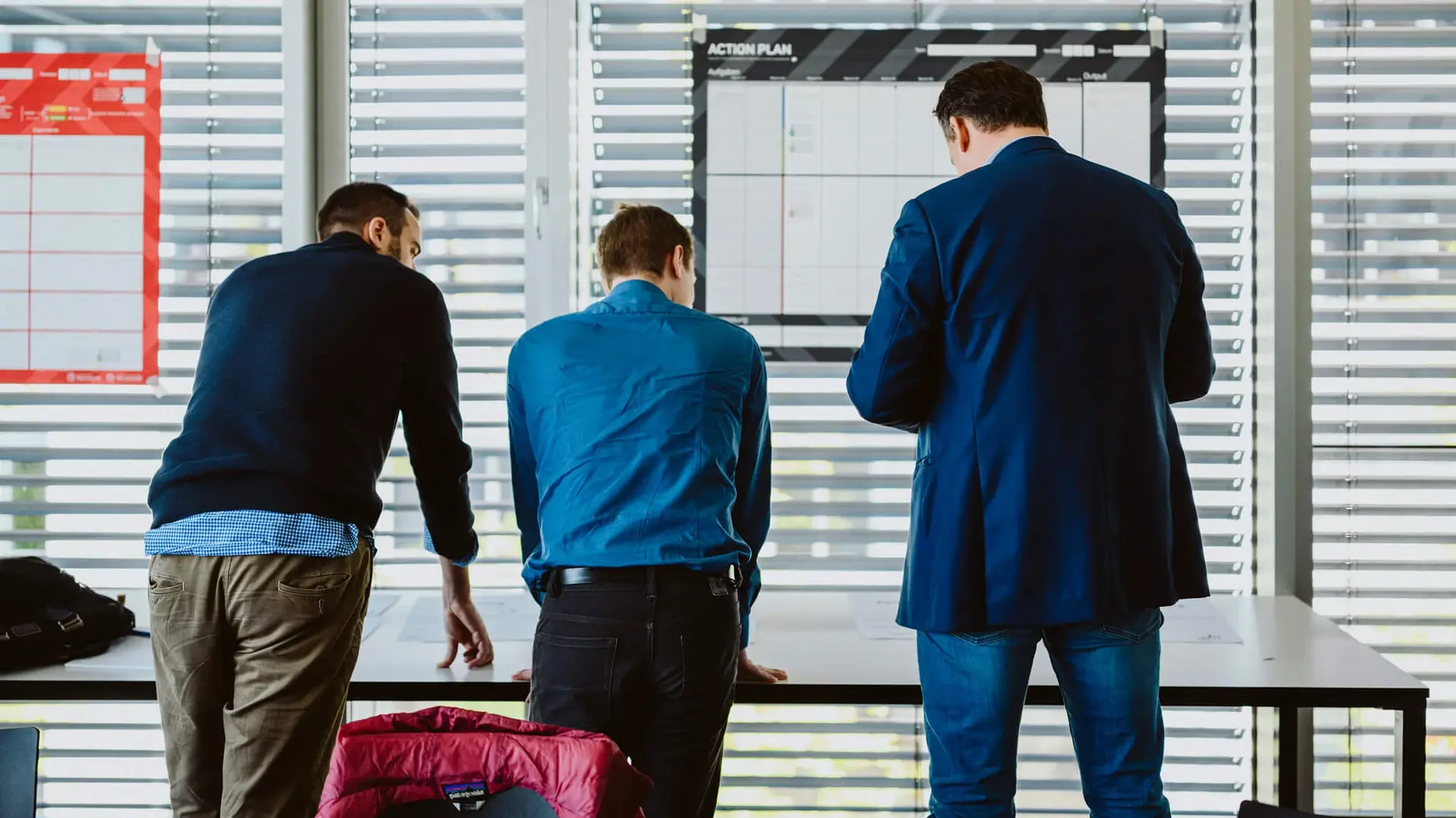 Drei Männer lehnen an einem Tisch und machen ein Brainstorming