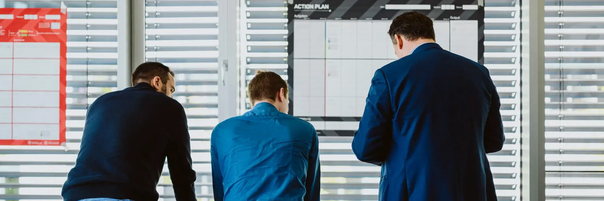 Three men leaning on a table and brainstorming