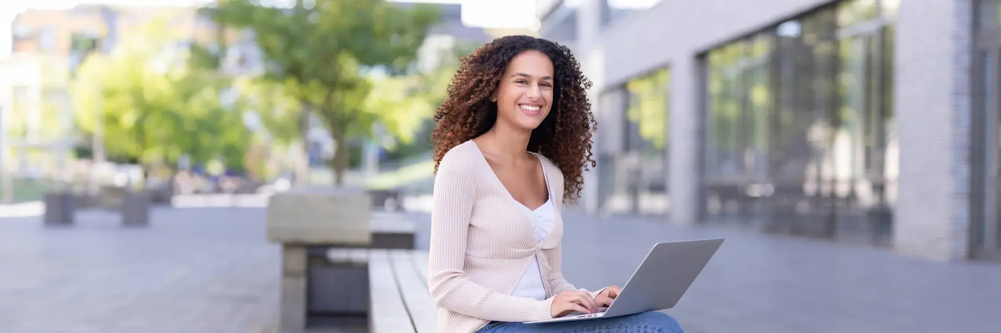 Ein Student arbeitet an einem Laptop draußen auf dem Campus