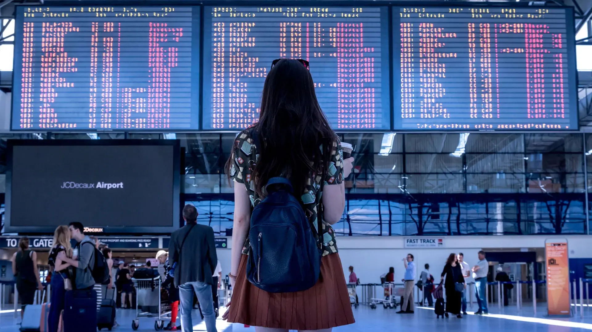 Eine junge Frau steht vor der Abflugtafel auf einem Flughafen